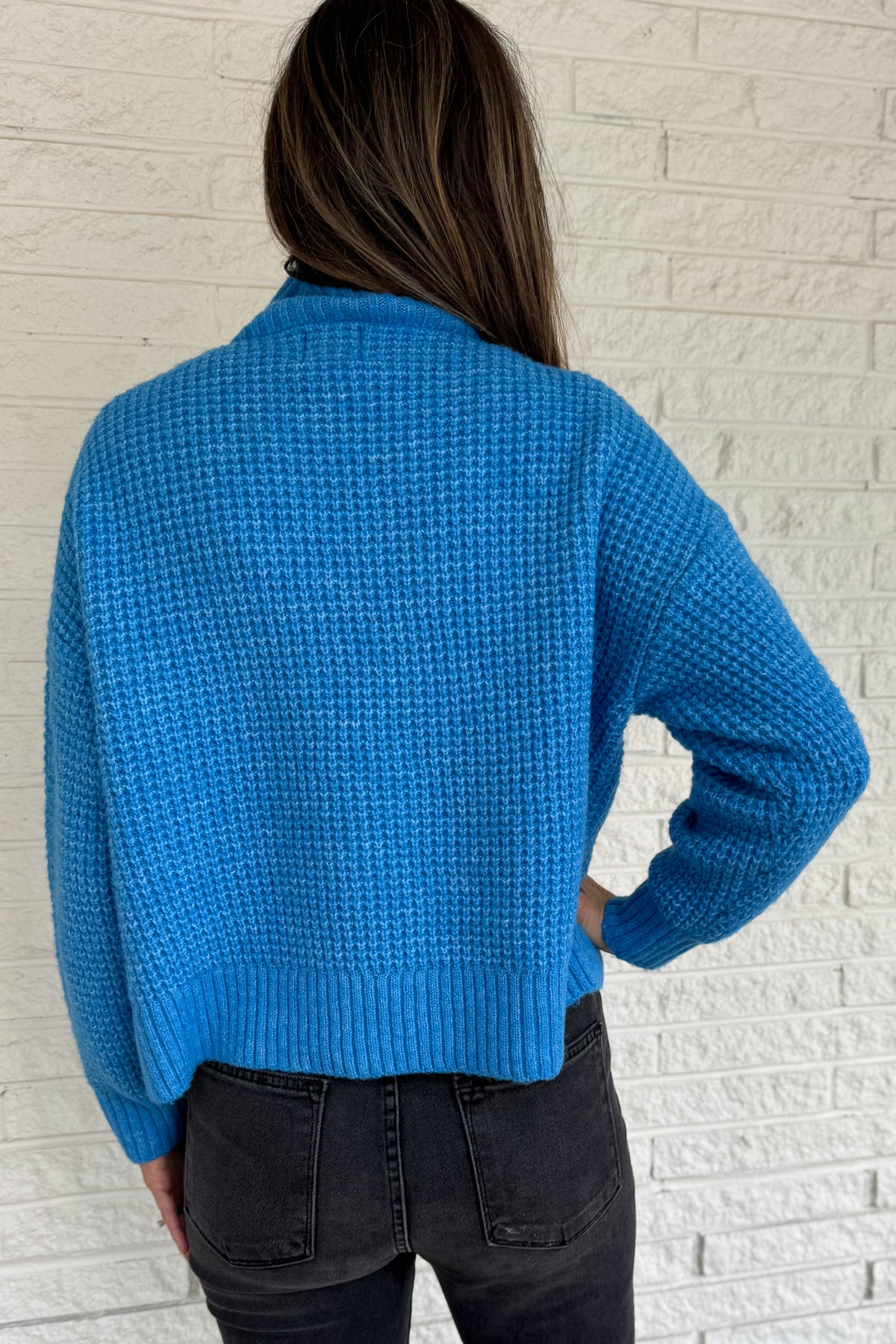 This bold blue oversized sweater brings warmth and style together in one easy piece. Knitted in a soft, textured “square” weave, it features a cozy stand-up collar and ribbed finishes that keep the look clean and structured. Perfect for pairing with denim or a skirt for effortless everyday wear.