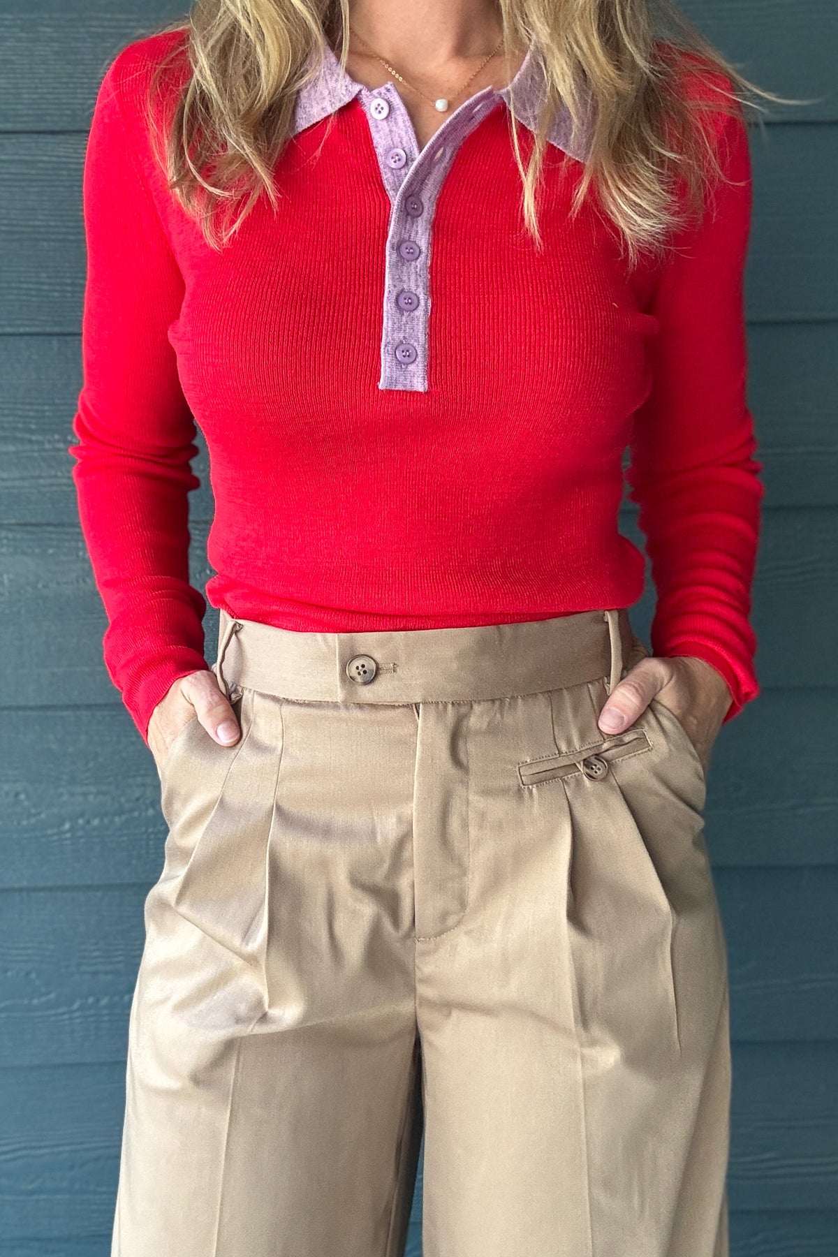 Close-up of women’s tan pleated trousers showing high waist, button closure, front pleats and pocket details.