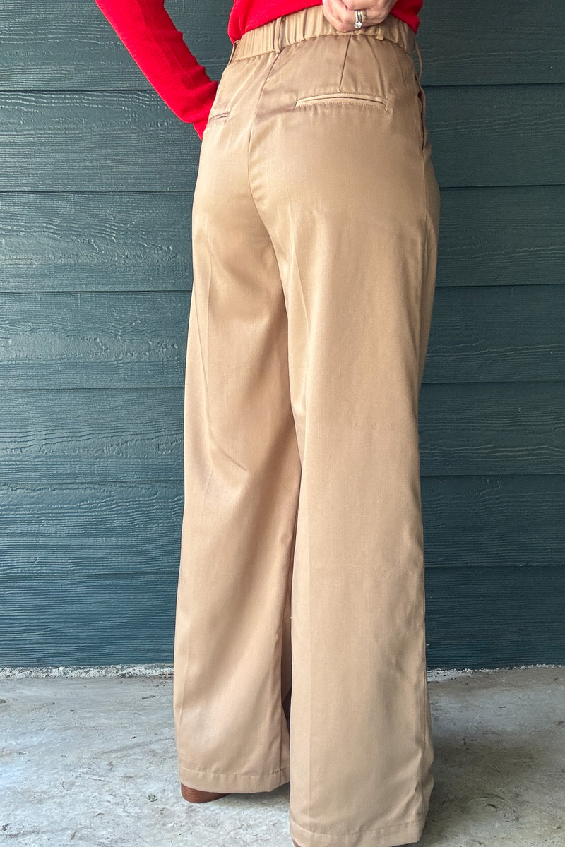Back view of women’s tan wide leg trousers with elastic back waistband, welt pockets and relaxed tailored fit.
