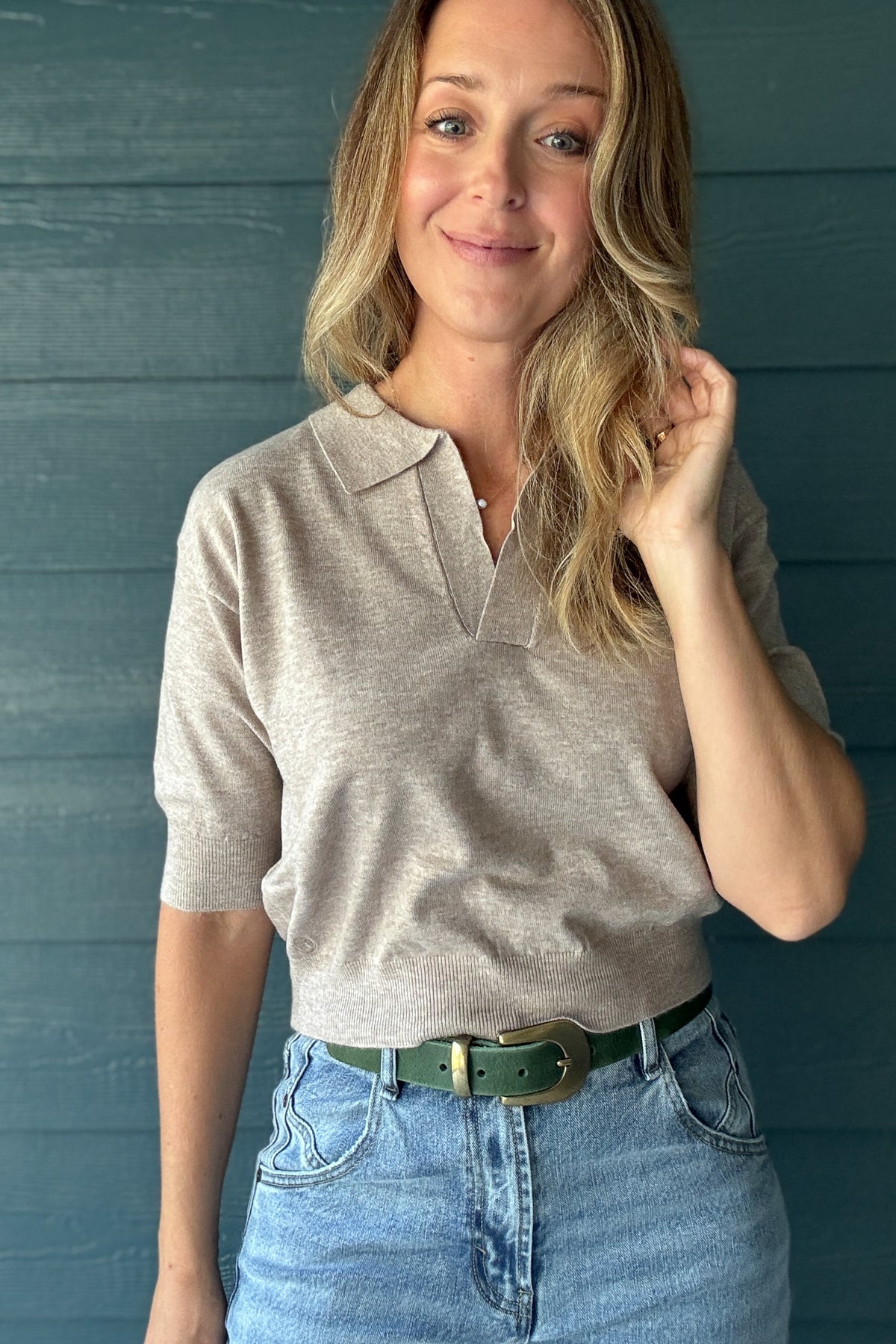 Taupe short sleeve knit polo sweater with open V-neck collar, relaxed fit and ribbed hem styled with denim.