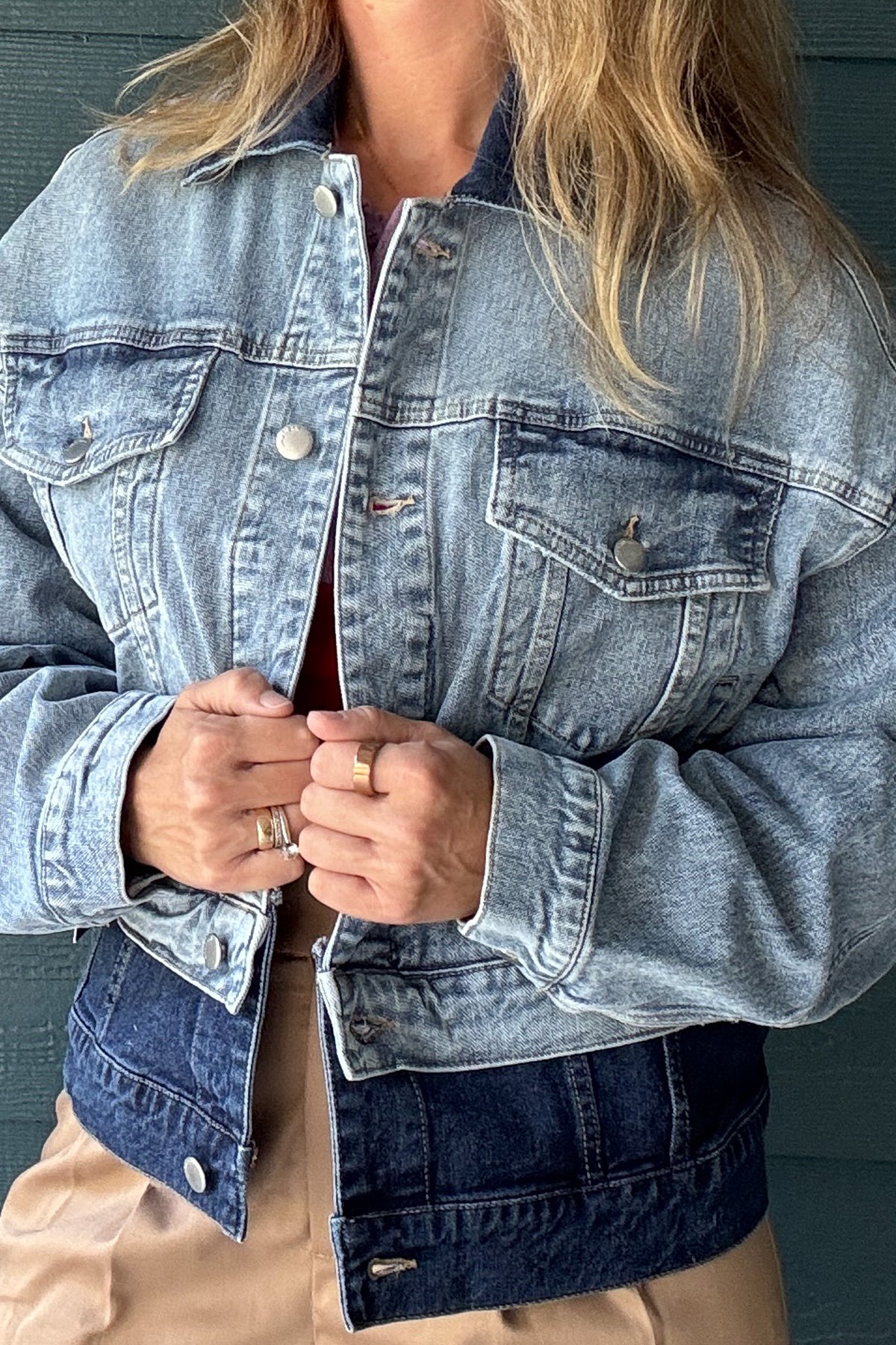Close-up of women’s two-tone denim jacket showing chest pocket, metal button, contrast stitching and dark denim collar.