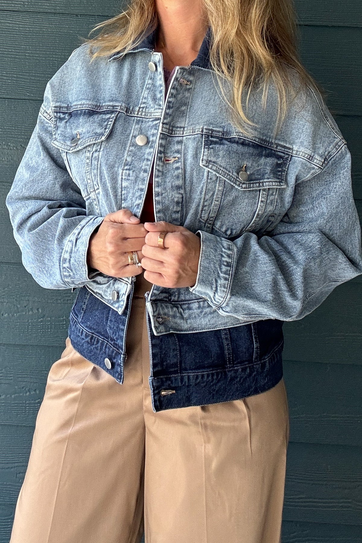 Back view of women’s two-tone denim jacket featuring light wash denim, dark wash lower panel and relaxed cropped fit.