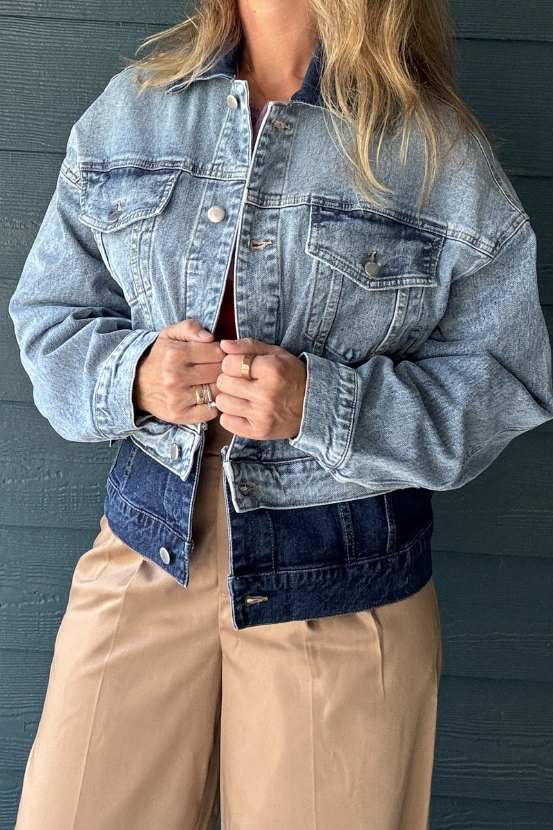 Back view of women’s two-tone denim jacket featuring light wash denim, dark wash lower panel and relaxed cropped fit.