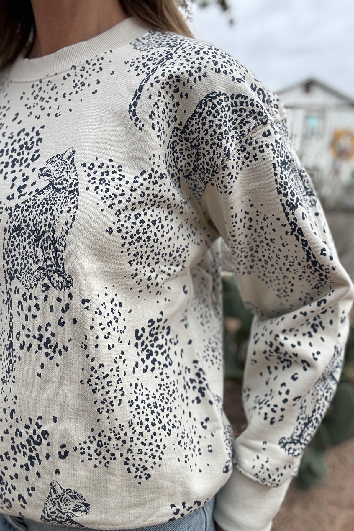 This cream sweatshirt features a soft neutral base with a subtle leopard print and cheetah motif throughout. Easy, relaxed, and made for everyday wear, it’s the kind of piece you’ll reach for on repeat. Perfect with denim, joggers, or layered under a jacket for effortless style.
