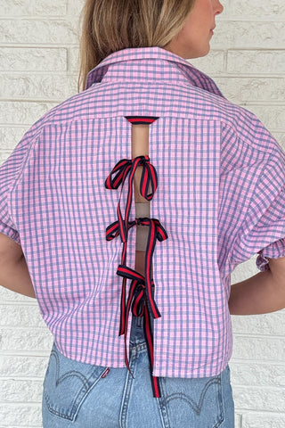 Front photo:
VonVie Harlow pink and blue plaid cropped button down shirt with puff sleeves and ruffled cuffs

Back photo:
Back view of VonVie Harlow pink and blue plaid shirt with open back and red and navy ribbon ties
