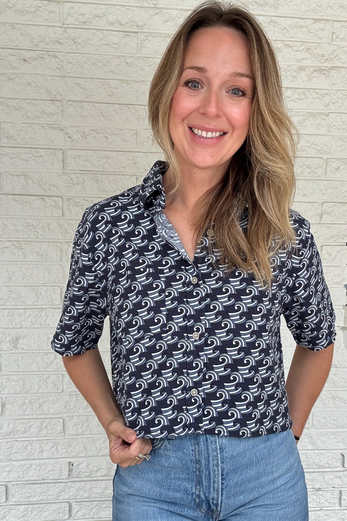 Front photo:
VonVie Harlow navy and white wave print cropped button down shirt with relaxed elbow length sleeves

Back photo:
Back view of VonVie Harlow navy wave print shirt with open back and red and navy ribbon ties