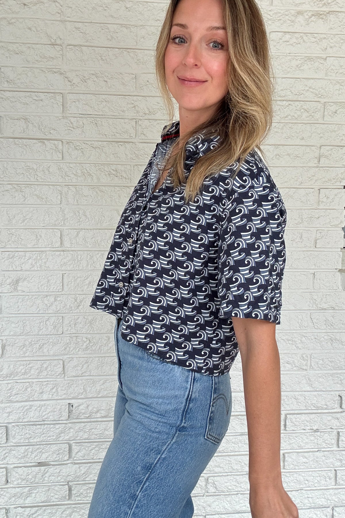 Front photo:
VonVie Harlow navy and white wave print cropped button down shirt with relaxed elbow length sleeves

Back photo:
Back view of VonVie Harlow navy wave print shirt with open back and red and navy ribbon ties