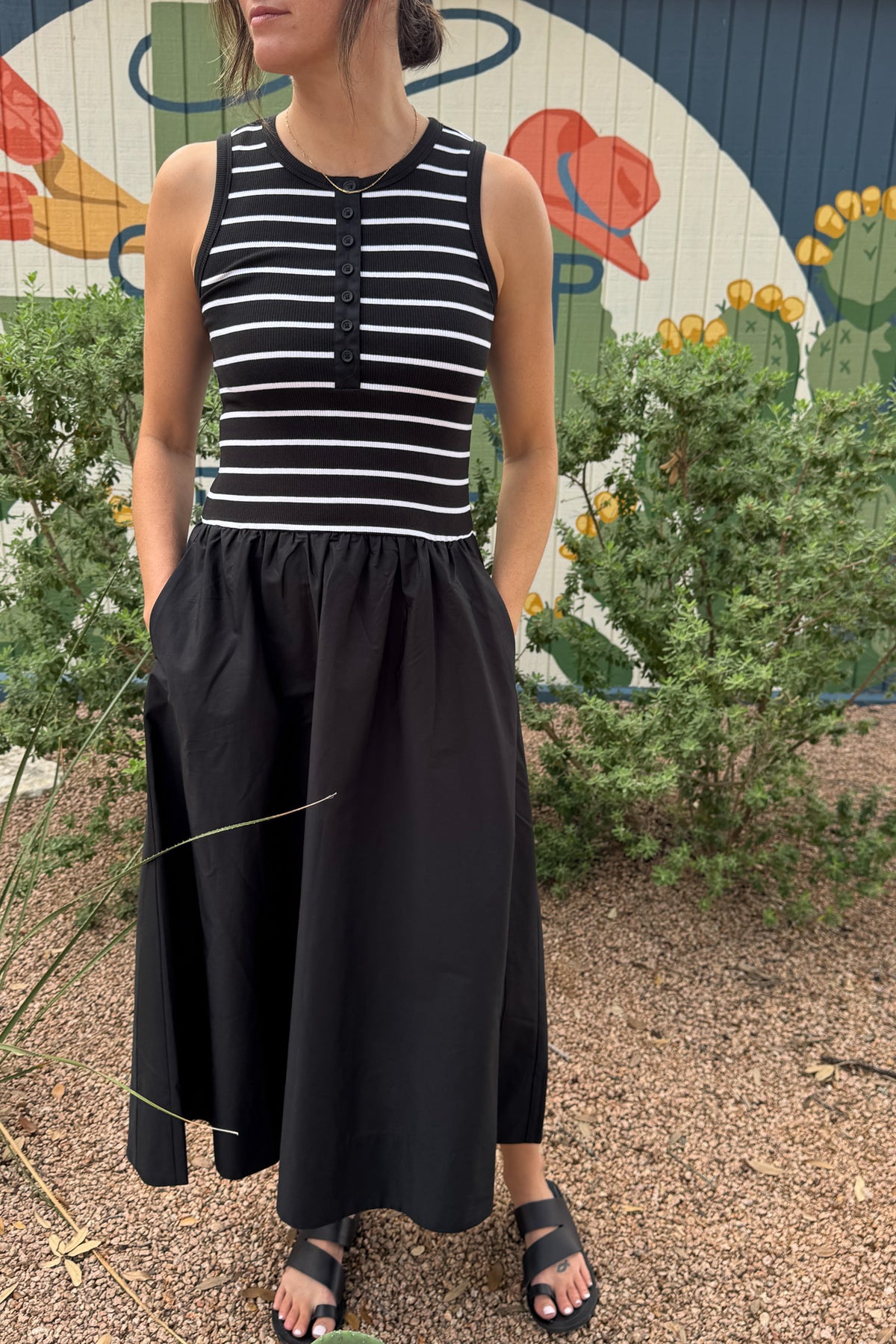 Women’s black midi dress with a fitted black and white striped ribbed bodice, button front, sleeveless cut and gathered full skirt with pockets.