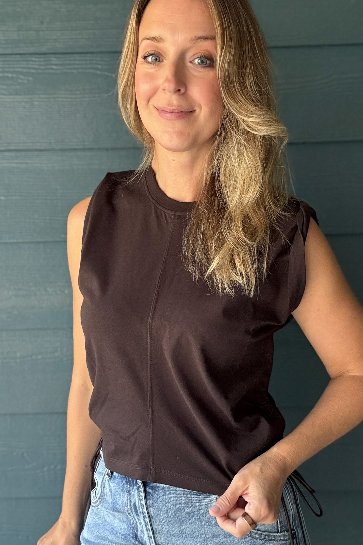 Women’s chocolate brown sleeveless top with a crew neckline, softly structured shoulders, center seam and adjustable side ruching.