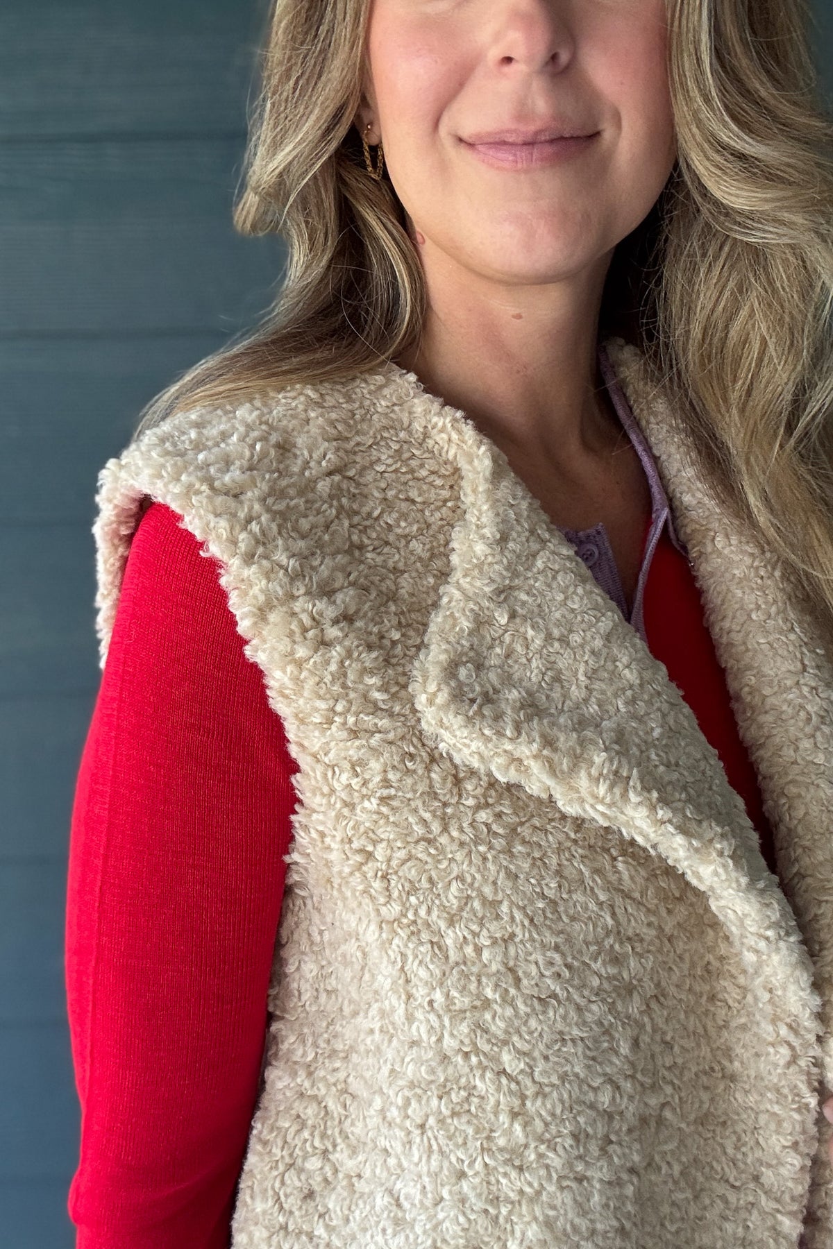 Women’s cream faux sherpa vest by Habitual Denim styled over a red long sleeve knit top with denim.