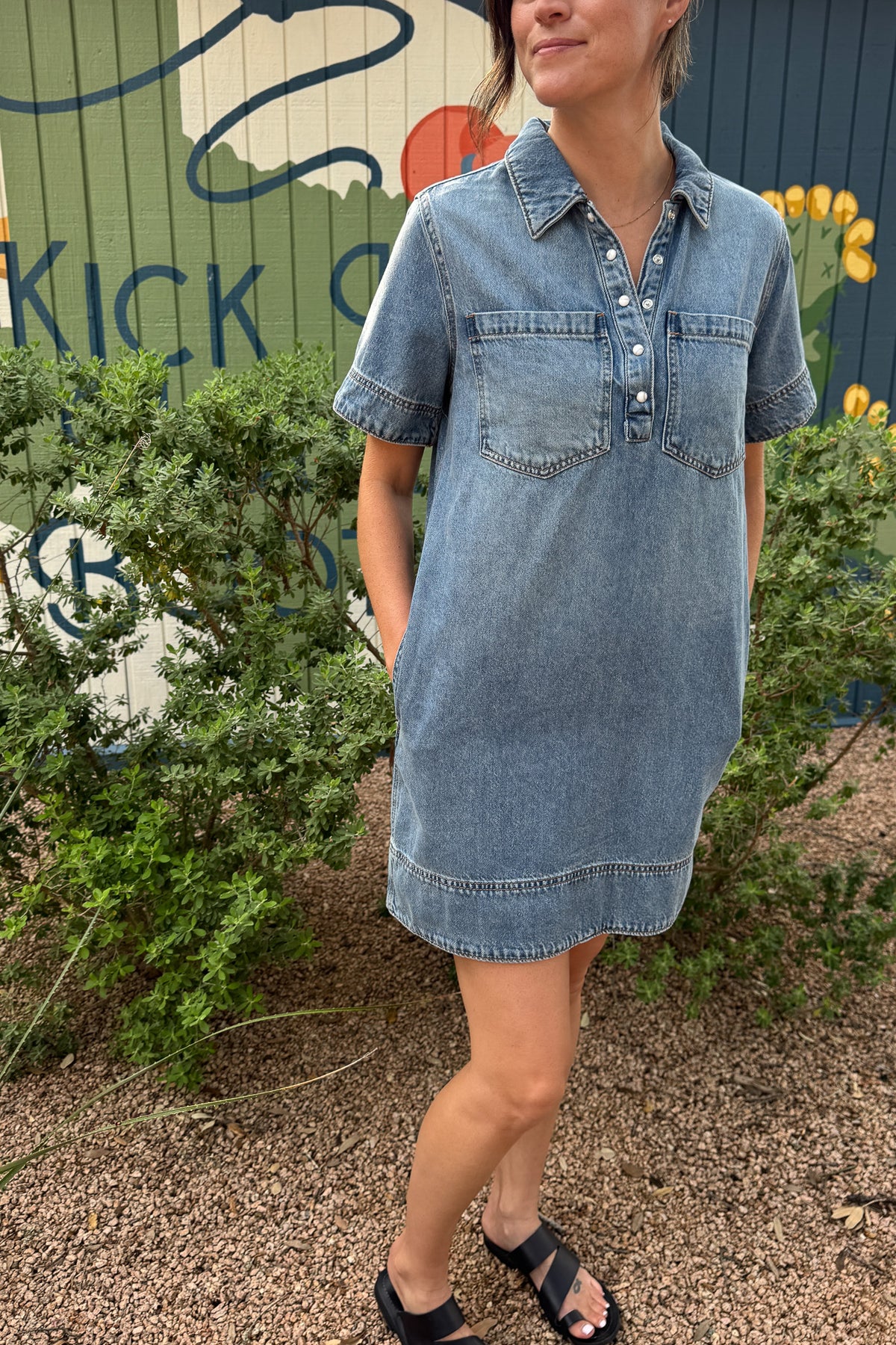 Women’s light wash denim shirt dress with short sleeves, pearl snap buttons and oversized chest pockets.
