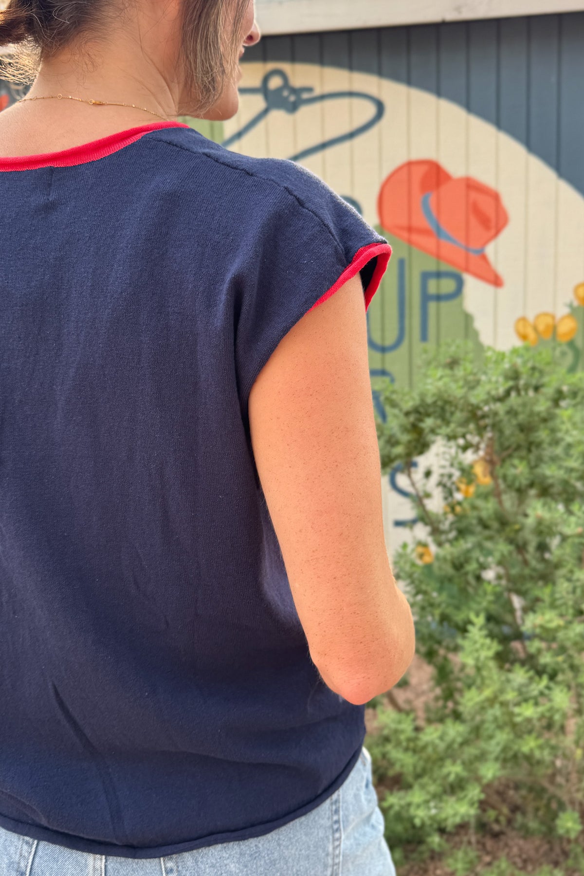 Back detail of a women’s navy cap sleeve top with red contrast trim around the neckline and sleeves.
