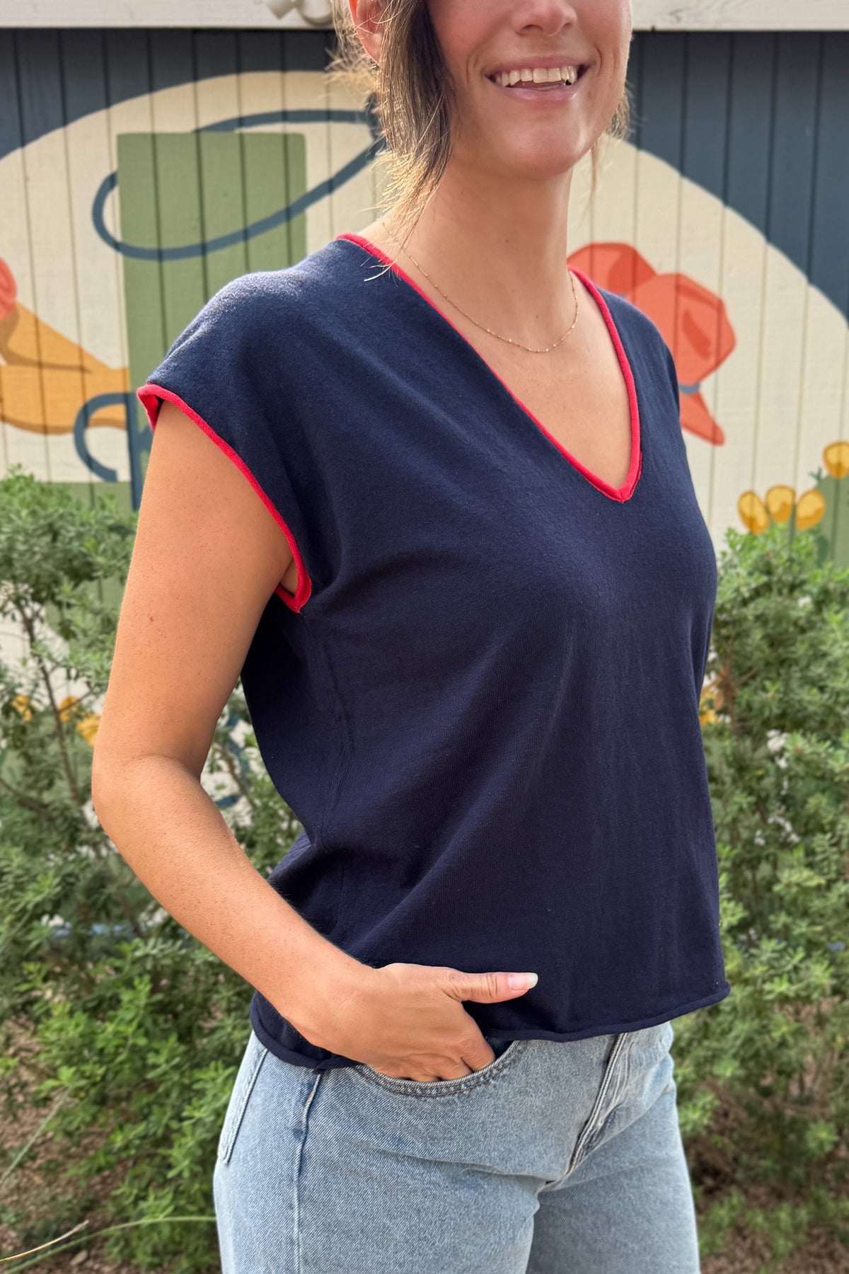 Women’s navy V-neck top with bright red contrast trim, cap sleeves and a relaxed everyday fit, styled with denim shorts.