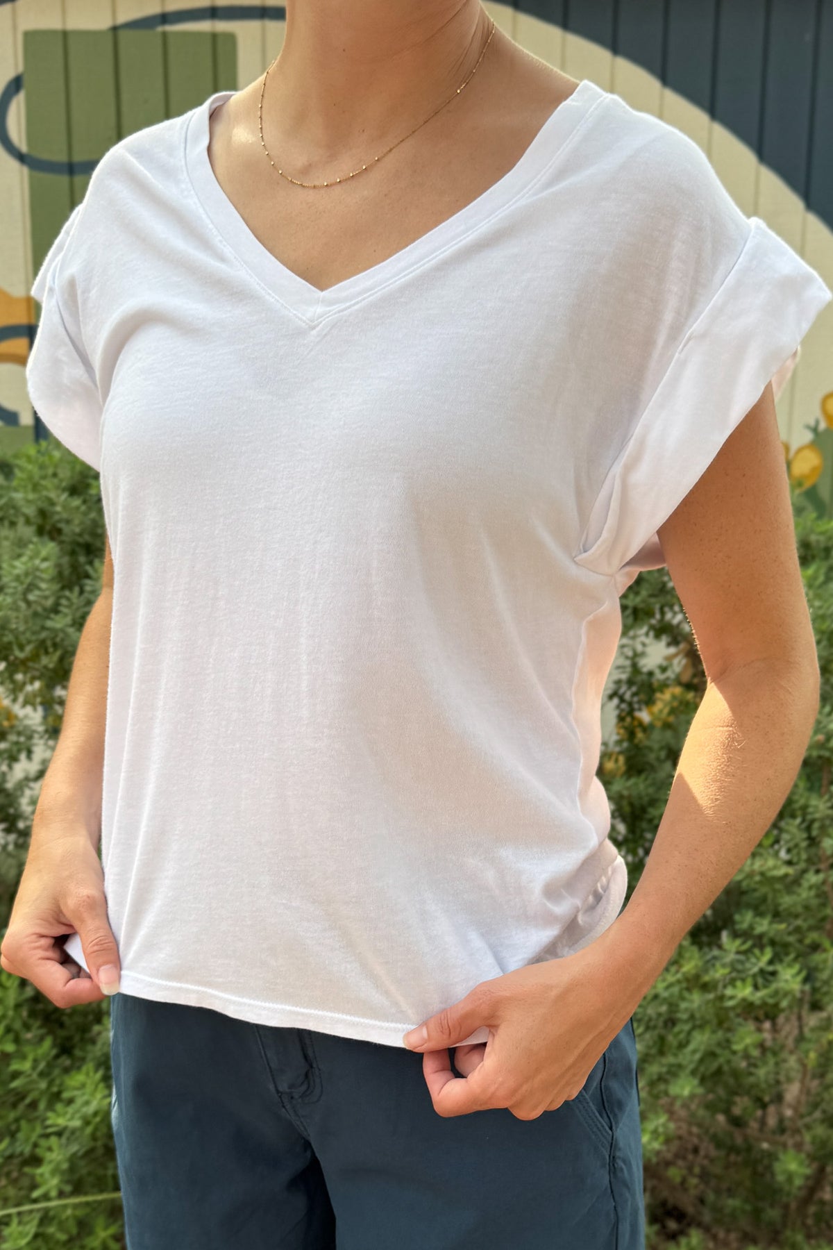 Front view of a women’s white V-neck top with wide cap sleeves, a relaxed silhouette and soft drape for easy everyday wear.